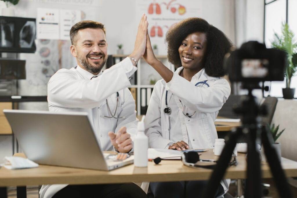 Diverse doctors giving high five during vlog recording