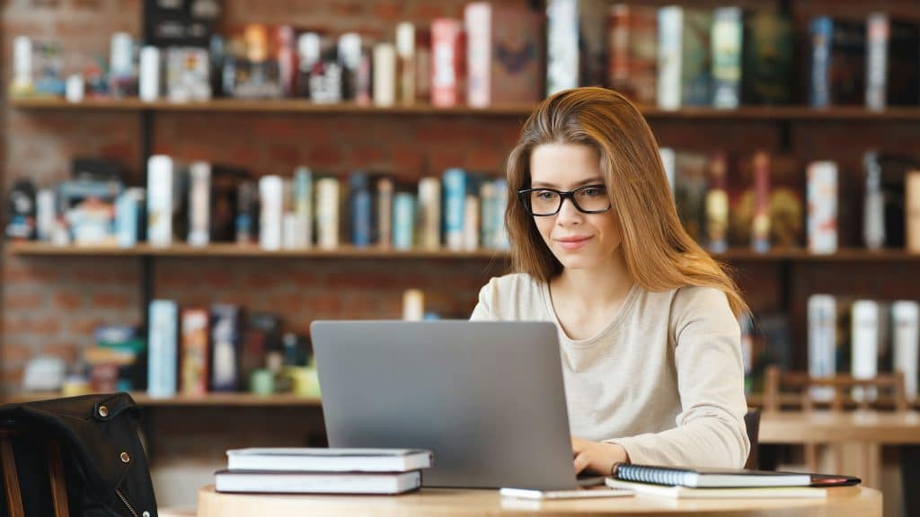 Trendy young girl freelancer writing private blog while resting in cafe